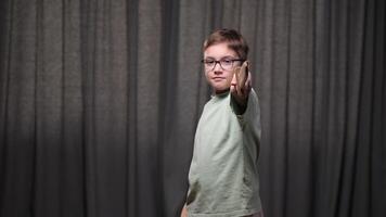 portrait of a boy with a wooden sword in his hand. The boy looks at the camera and points the sharpest sword at the camera. A boy with glasses plays a knight, a warrior with a sword video