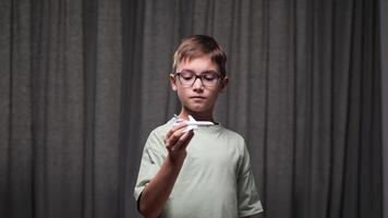 Boy with glasses plays with a toy airplane, lost in imagination and dreaming of flying as a future pilot, embodying adventure and ambition video