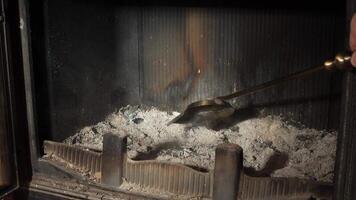 Housekeeper scoops ashes from a fireplace using a metal shovel, maintaining cleanliness and safety in the home. The process highlights the importance of regular fireplace maintenance video