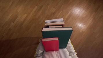 pov First person view Student carries a stack of books on a wooden floor, preparing for exams with determination and focus. Ideal for showcasing learning and exam preparation video