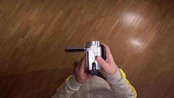 pov First person view Videographer adjusts a camcorder, handycam in a room with a parquet floor, getting ready to film. recording starts, showcasing production technology video
