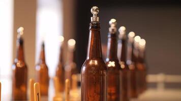 Empty brown bottles in a brewery, neatly lined up for filling and quality control. Amber glass bottles on a metal table, inspected for high standards video