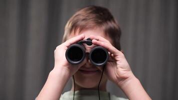close-up portrait Young boy holds binoculars to his eyes, engaging in imaginative exploration and discovery, his face lit with a sense of wonder and adventure video