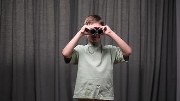 Young boy holds binoculars to his eyes, engaging in imaginative exploration and discovery, his face lit with a sense of wonder and adventure video