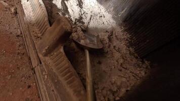 first-person view pov a shovel rakes ashes out of a fireplace. A person cleans a stone from ashes. Ashes are raked into a bucket from a home fireplace. Fireplace maintenance video