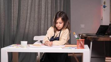 little girl immerses in her drawing, showcasing dedication and focus while creating at her desk. The scene captures a moment of creativity and concentration in a peaceful environment video