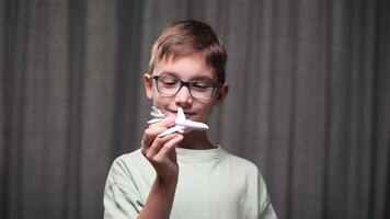 boy playing with airplane model. Boy dreams of becoming a pilot. Child dreams of flying on an airplane. Dreams of traveling on an airplane. Child's dream concept. Boy with glasses holding a toy video