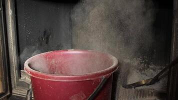 Housekeeper is removing cold ashes from a fireplace using a metal shovel and a bucket. He carefully scoops the ashes to avoid creating dust video
