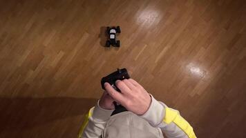 pov First-person view of a person using a remote control to operate a radio-controlled car on a wooden floor, providing a playful and engaging perspective on indoor hobbies video