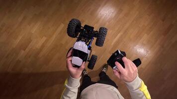 pov Person holding a radio-controlled car upside down and the remote control, ready to play inside a house with a parquet floor video