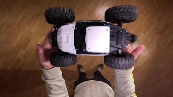 pov man throws a model car up into the air. First-person view of a person Holding a radio-controlled car indoors on a wooden floor, ready to play and have fun video