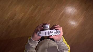 pov First person view Photographer adjusting settings on a vintage rangefinder camera while standing on a wooden parquet floor, seen from a first-person perspective. Take a picture on old camera video