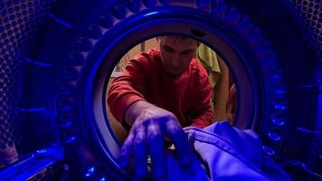 pov Man loading dirty clothes into the washing machine. Man opening the door of the washing machine. View from inside the washing machine. Man in a modern bathroom loads laundry video