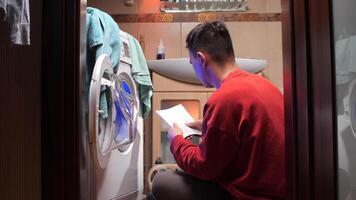 a man tries to figure out how to operate and use a washing machine with the help of the manual. A man leafs through the paper manual for a washing machine video