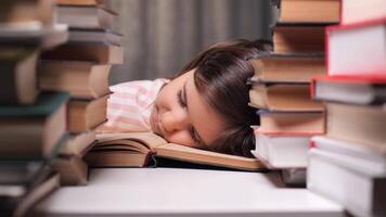little girl got tired of learning to read and fell asleep on a book. The concept of children getting tired of learning. The little girl read enough fairy tales and fell asleep among stacks of books video