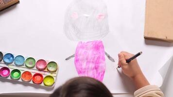 top view little girl Young artist carefully adding details to a colorful cartoon character drawing with a pink marker showcases creativity and imagination in a joyful, focused environment video