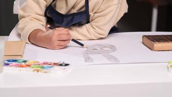 Close-up view of a child artist sketching a bunny rabbit face with a pencil on white paper. The focus highlights the creativity and concentration involved in the drawing process. a little girl draws video