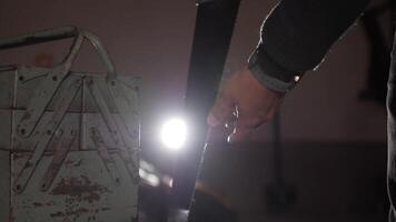 Worker inspecting saw blade. close up of hand saw in garage. Construction worker inspecting a saw blade for damage using a flashlight in a dimly lit environment video