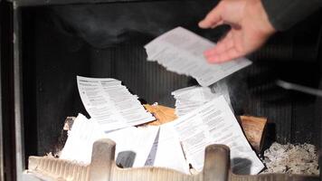 man destroys documents in a fireplace. A man throws documents into a fire. Accountant throwing piles of tax forms into a fireplace creates a dramatic scene of destruction video