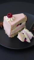 Piece of sweet cake with pink cream with raspberry flavor, with shortbread, cheesecake on a dark concrete background video