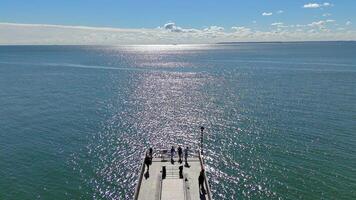 Aerial view of a sparkling ocean with pier, people enjoying the view at Coney Island Beach video