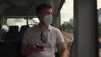Man sits on bus wearing protective mask ffp2 uses smartphone in Germany, Munich. Passenger in protective mask in public transport and surfing Internet. Coronovirus rules of personal protection video