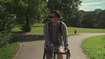 Cyclist uses smartphone on handlebars of bicycle to navigate. Male bicyclist rides his bike in park in Germany and use GPS to find way around. Man planning route application in mobile phone. video