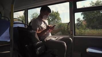 Man sits on bus wearing protective mask ffp2 uses smartphone in Germany, Munich. Passenger in protective mask in public transport and surfing Internet. Coronovirus rules of personal protection video