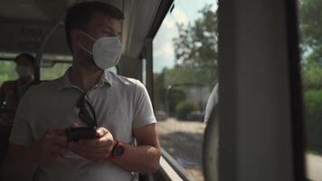 Commuting during pandemic. Public transportation curfew. Using cell phone while commuting to work on public transportation bus while wearing mask to prevent corona virus. Social distancing on bus video