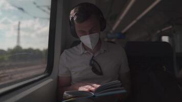 Passenger traveling on Deutsche train in summer with wireless headphones and reading book. Student reads study workbook with wireless earphones while commuting on train. Daily commute to university. video