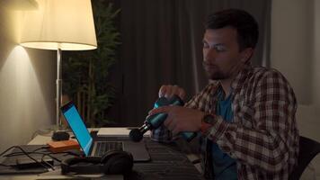 cervical nacke värk, nerv artrit. man studerar sent genom natt på bärbar dator dator med cervical smärta. utmattad kille avkopplande hans nacke använder sig av pistol massager medan överansträngning på anteckningsbok dator. video