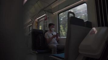 Tourist on passenger train in Germany using a smartphone application, wearing protective mask. Railroad passenger holding a mobile phone during a journey on a train with a KN95 FFP2 protective mask. video