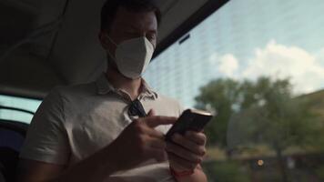 Commuting during pandemic. Public transportation curfew. Using cell phone while commuting to work on public transportation bus while wearing mask to prevent corona virus. Social distancing on bus video
