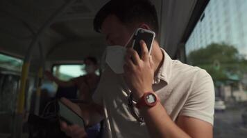 Man sits on bus wearing protective mask ffp2 uses smartphone in Germany, Munich. Passenger in protective mask in public transport and surfing Internet. Coronovirus rules of personal protection video
