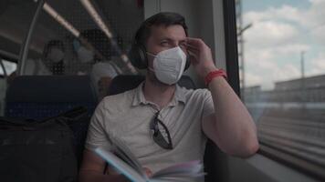Passenger traveling on Deutsche train in summer with wireless headphones and reading book. Student reads study workbook with wireless earphones while commuting on train. Daily commute to university. video