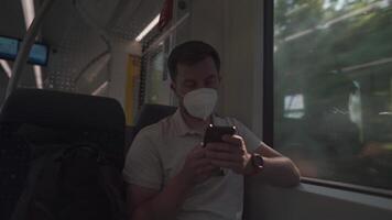 Tourist on passenger train in Germany using a smartphone application, wearing protective mask. Railroad passenger holding a mobile phone during a journey on a train with a KN95 FFP2 protective mask. video