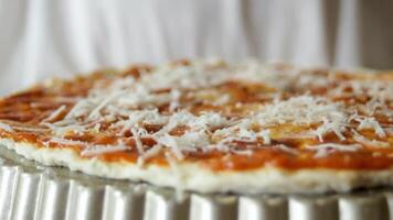 The grated cheese lays beautifully on the dough covered with tomato sauce. A close-up of the pizza preparation. video