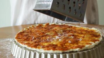 Grated cheese falls on the dough. Making pizza. Cheese is grated on the dough with sauce. video