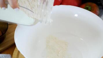 Hand holding a jar of flour and sifting it into a plate. video