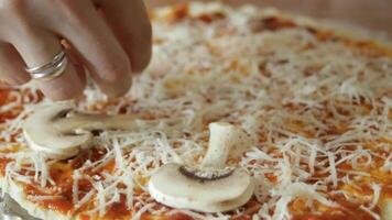 The chef's hand lays out fresh slices of scallion mushrooms in a circle on a prepared dough base covered with sauce and cheese. video