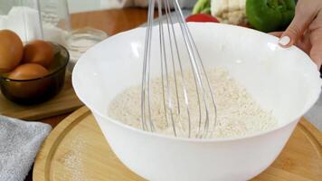 Mixing flour with spices using a kitchen whisk. Stirring the mixture in a white plate on a round board. video