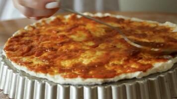 The chef applies a juicy tomato sauce to the pizza base. Cooking pizza in close-up. video