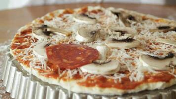 Laying out sausage rings on a pizza base. Slices of spicy pepperoni sausage are placed on the dough with sauce, cheese and mushrooms. video