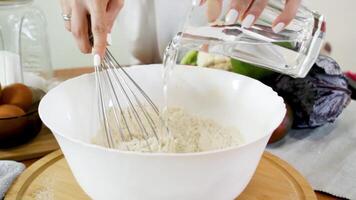Pour water into the mixture with flour and spices and stir. Mix the mixture with a hand whisk. video