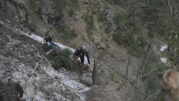 Man cyclist pulls bicycle through avalanche in mountains. Bicyclist is trapped in obstacle and is pulling his cycle through an ice slide with bicycle in his hands. Avalanche on cycling route in Alps. video