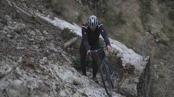 Man cyclist pulls bicycle through avalanche in mountains. Bicyclist is trapped in obstacle and is pulling his cycle through an ice slide with bicycle in his hands. Avalanche on cycling route in Alps. video