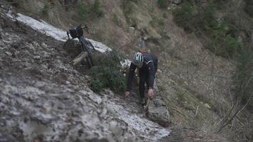 Man cyclist pulls bicycle through avalanche in mountains. Bicyclist is trapped in obstacle and is pulling his cycle through an ice slide with bicycle in his hands. Avalanche on cycling route in Alps. video