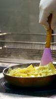 Cooking and stirring pasta in frying pan. Pasta with sauce turned with spatula in a frying pan. Cooking dinner concept. Vertical video
