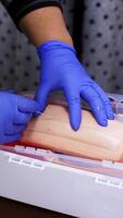Hands in gloves making injection with a syringe for puncture. Simulation medical training model. Medical procedure concept, simulation medicine training. Vertical video