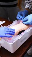 Doctor in gloves making injection with a syringe for puncture. Simulation medical training model. Medical procedure concept, simulation medicine training. Vertical video